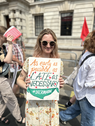 Placard which reads "As early as possible, as late as necessary/#decrim now"