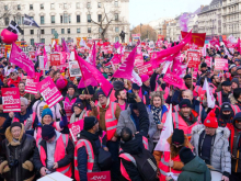 Photo of a CWU rally with attendees in pink hi-vis vest, waving pink union flags