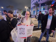Adam Keller holding signs that say "No to war - Yes to peace" and the other one says "All for All" (i.e. all Palestinian prisoners in Israeli prisons in exchange for all captive Israelis in Gaza). 