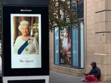 Homeless man sitting by image of the queen