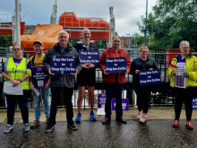 Lecturers on a picket line holding signs that say "Stop the Cuts to Stop the Strike"