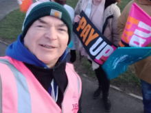 A man wearing a pink hi-vis on an NEU picket line