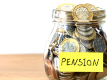 A jar of pound coins with a yellow label reading "Pension"