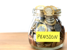 A jar full of pound coins with a yellow sticker on it, labelled "Pension"