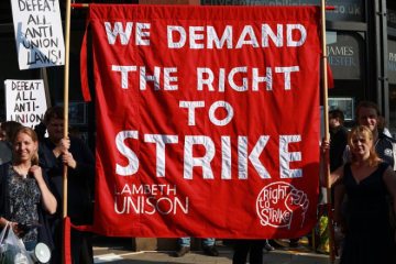 A large red banner with the slogan "We demand the right to strike" and "Lambeth Unison" embroidered on it