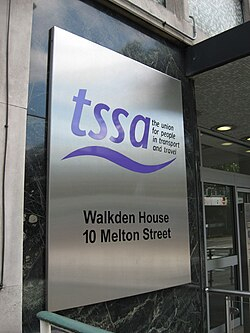 Metal sign outside the former TSSA headquarters reading "tssa – the union for people in transport and travel," with the address "Walkden House, 10 Melton Street." A glass entrance door is visible beside the sign.